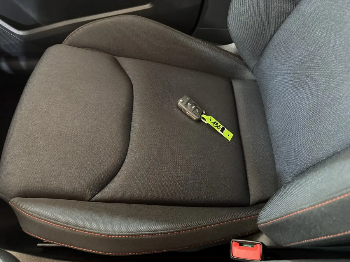 Gros plan sur le siège avant droit noir avec surpiqûres rouges et clé de voiture SEAT Ibiza 2024 posée dessus.