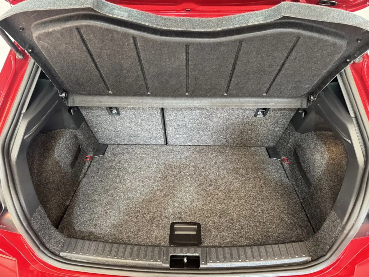 Coffre ouvert vu de face d'une SEAT IBIZA 1.0 TSI 110 FR rouge, montrant l'espace de chargement vide et doublure grise.