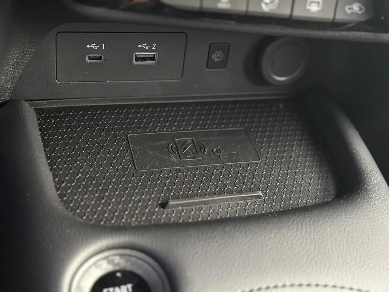 Gros plan sur la zone de recharge sans fil et ports USB du Nissan Juke 2025 gris foncé, intérieur noir.