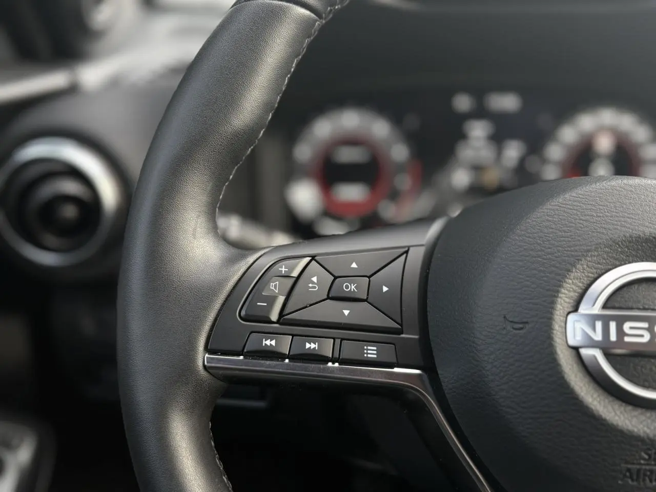 Gros plan sur le volant en cuir noir du Nissan Juke 2025, avec commandes multifonctions visibles côté gauche.