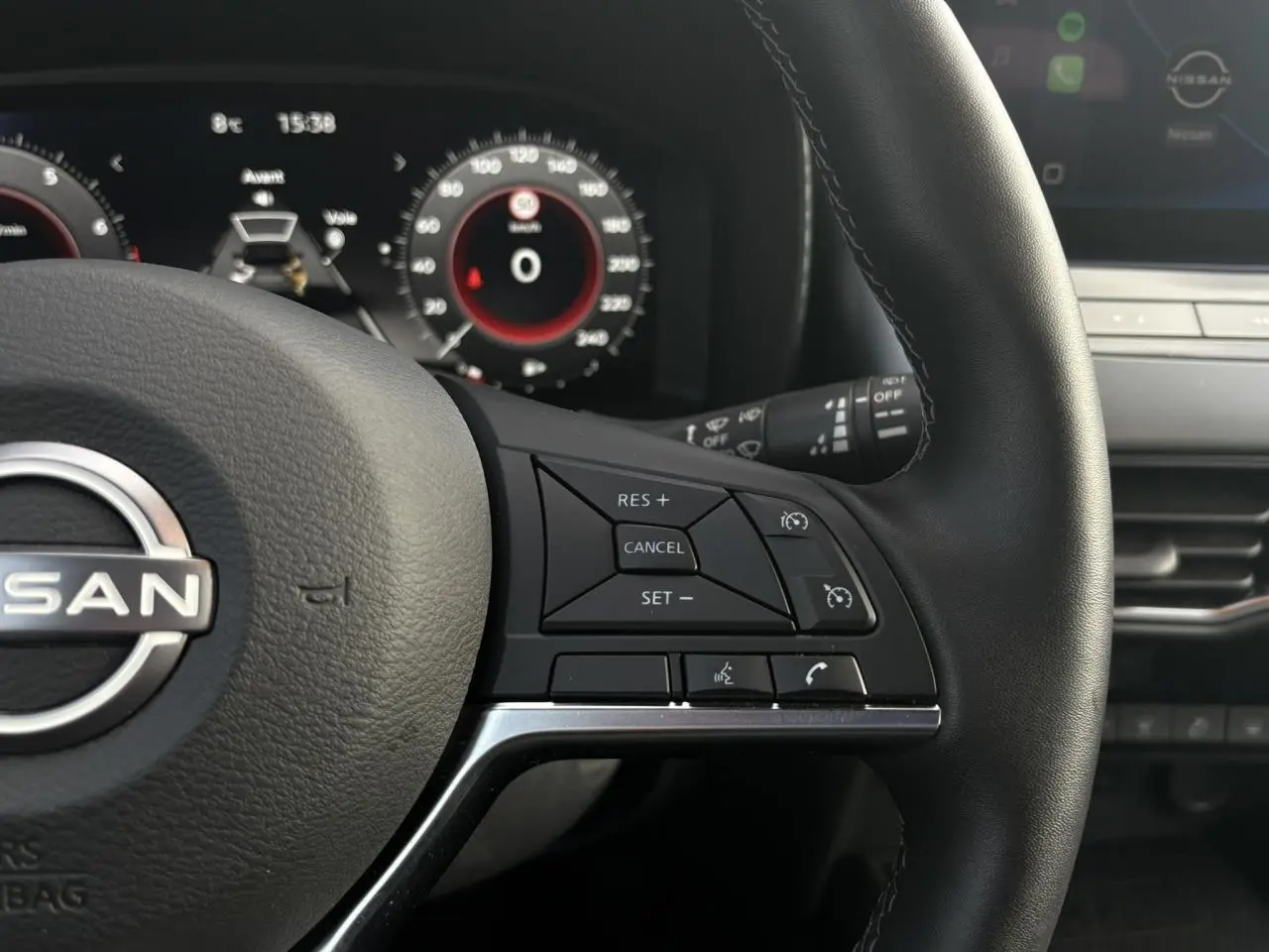 Gros plan sur le volant cuir noir côté droit du Nissan Juke 2025 avec commandes de régulateur de vitesse et tableau de bord digital.