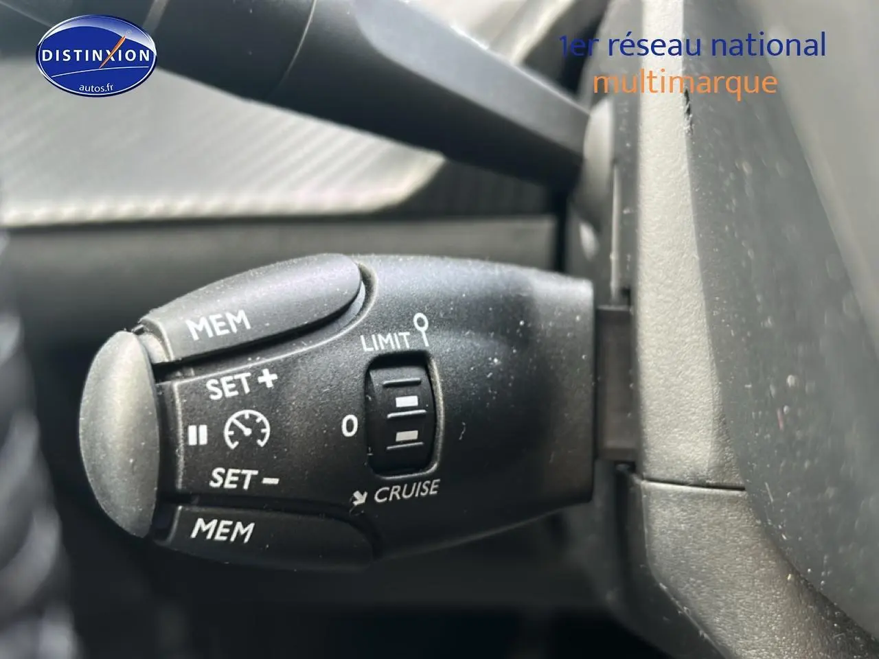 Commande de régulateur de vitesse et limiteur sur le volant d'une Peugeot 208 gris artense, vue rapprochée côté gauche.