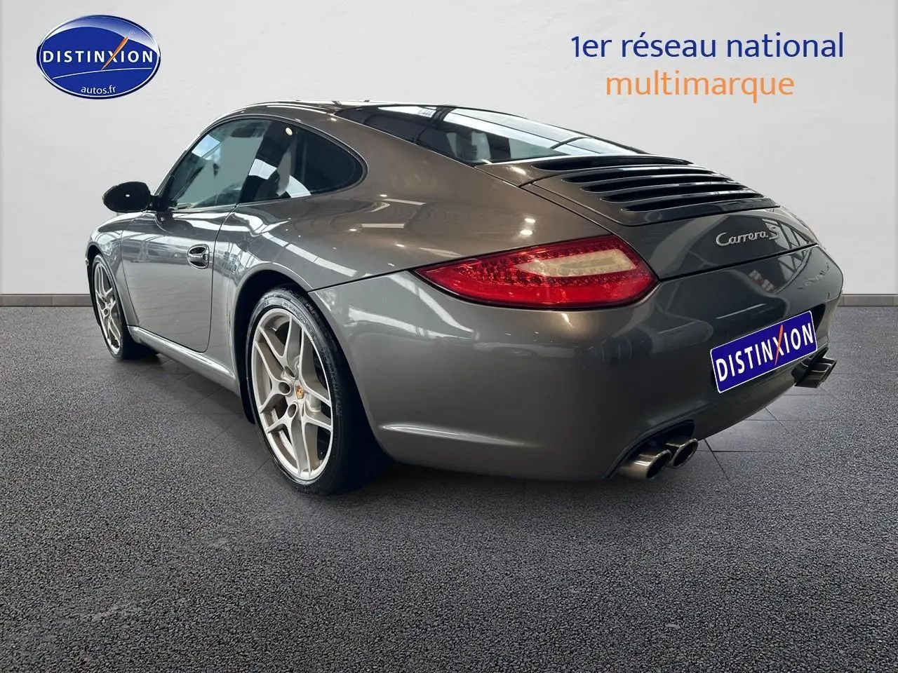 Vue 3/4 arrière droite d'une Porsche 911 (997) Carrera gris métallisé avec jantes alu et feux arrière allongés.