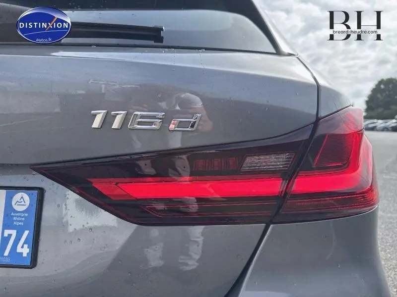 Gros plan sur le feu arrière droit et le badge 116d d'une BMW Série 1 gris Skyscraper métallisé.