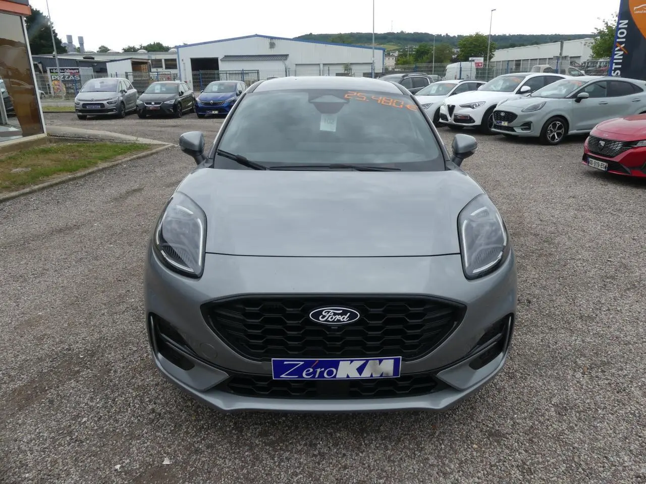 Vue frontale d'une Ford Puma 2025 gris métallisé avec calandre noire et plaque Zéro KM visible.