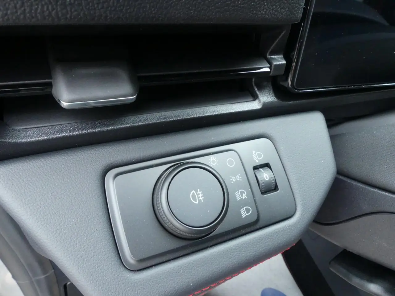 Gros plan sur la commande des feux avec molette et réglage d'intensité dans le tableau de bord du Ford Puma 2025 gris métallisé.
