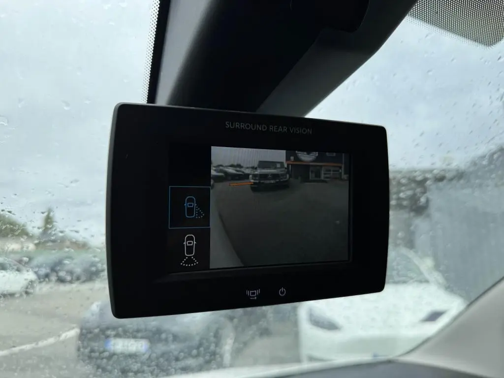 Écran de caméra de recul du Citroën Berlingo blanc montrant l'arrière et un véhicule garé en extérieur sous la pluie.