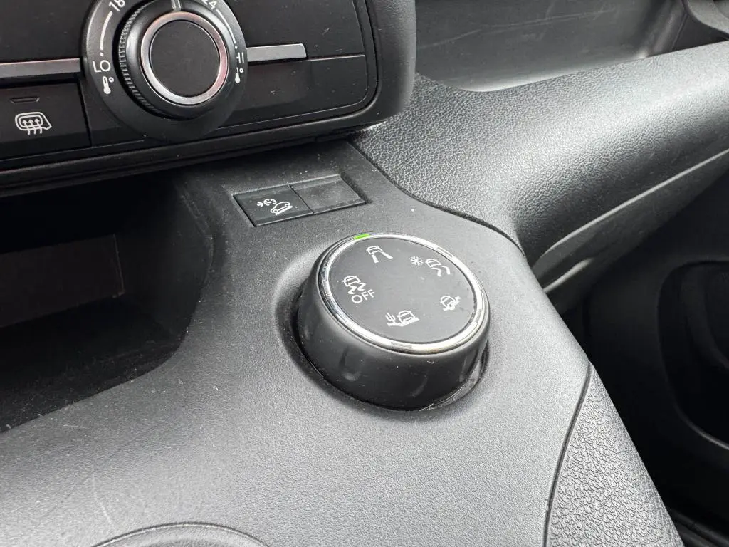 Gros plan sur la molette de contrôle des aides à la conduite dans l'habitacle noir du Citroën Berlingo blanc 2019.