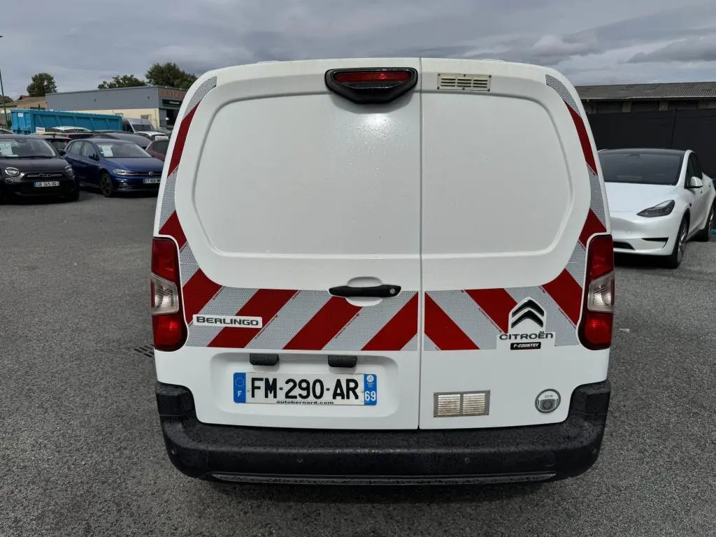 Vue arrière d'un Citroën Berlingo blanc avec bandes réfléchissantes rouges et blanches et plaques d'immatriculation françaises.