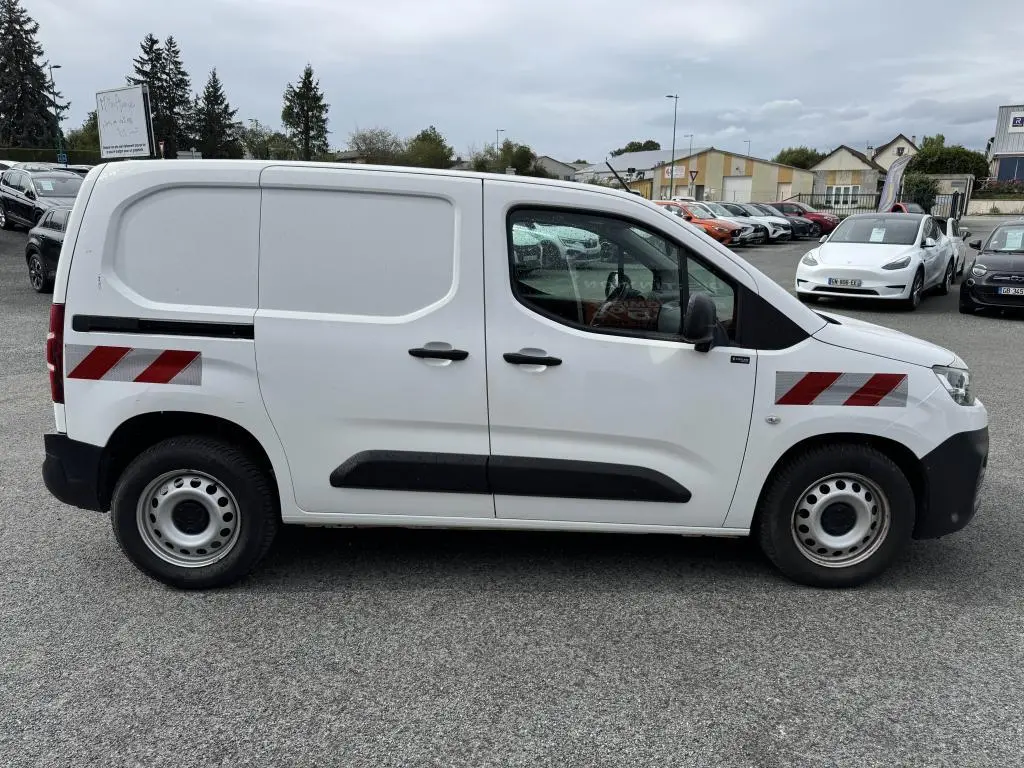 Vue latérale droite d'un utilitaire Citroën Berlingo blanc avec bandes réfléchissantes rouges et noires sur les portes.