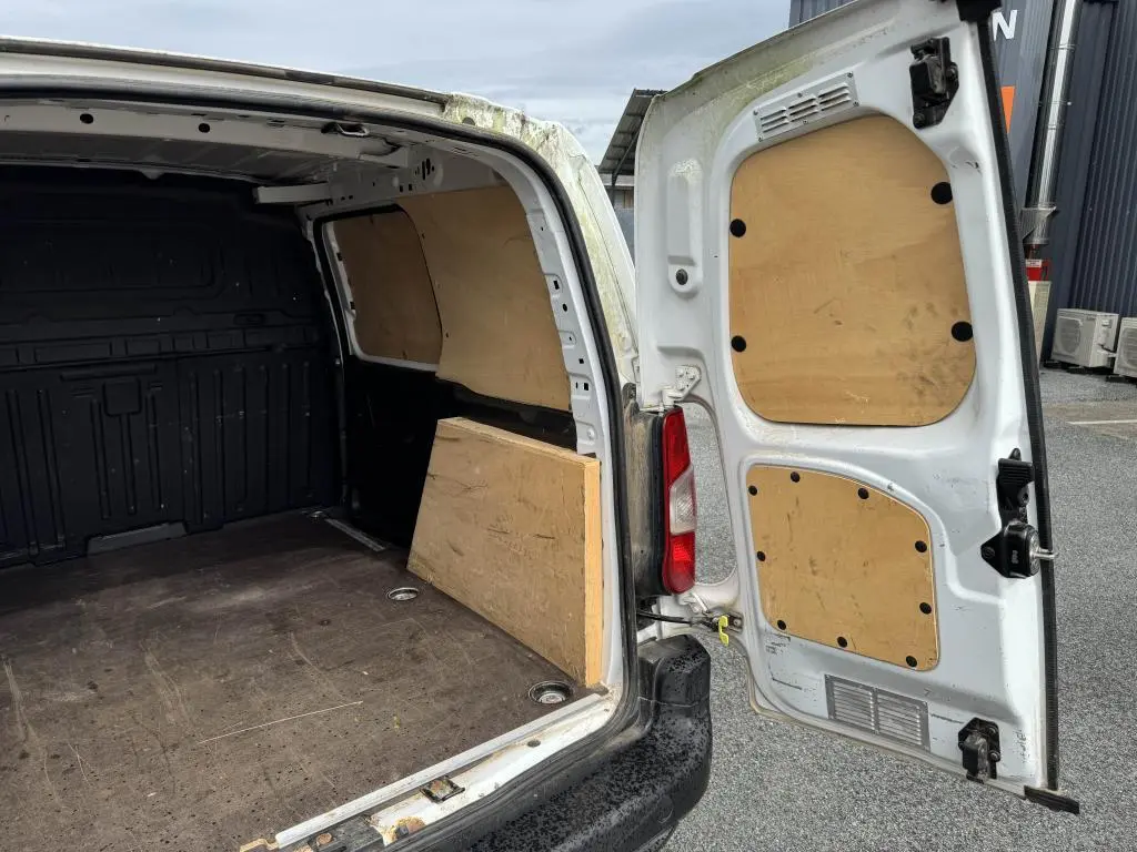 Vue intérieure arrière du Citroën Berlingo blanc avec portes battantes ouvertes et aménagements en bois dans la zone de chargement.