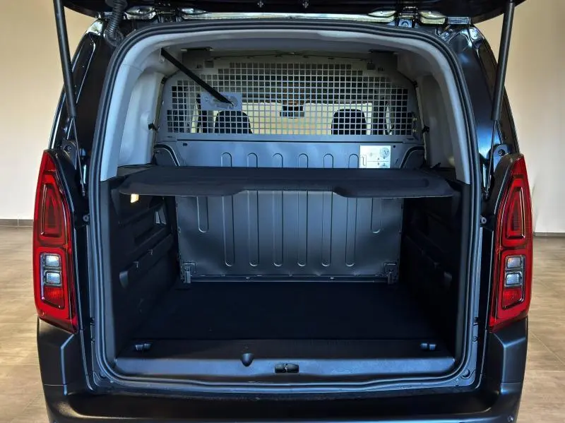 Coffre ouvert vu de l'arrière du Citroën Berlingo Fourgon noir Perla Nera nacré avec cloison métallique et tablette de séparation.