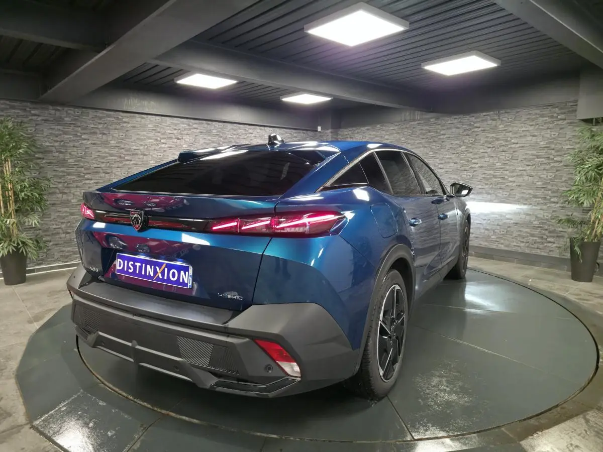 Vue 3/4 arrière droite d'une Peugeot 408 hybride rechargeable bleu métallisé avec feux arrière LED griffés et jantes alliage 19 pouces.