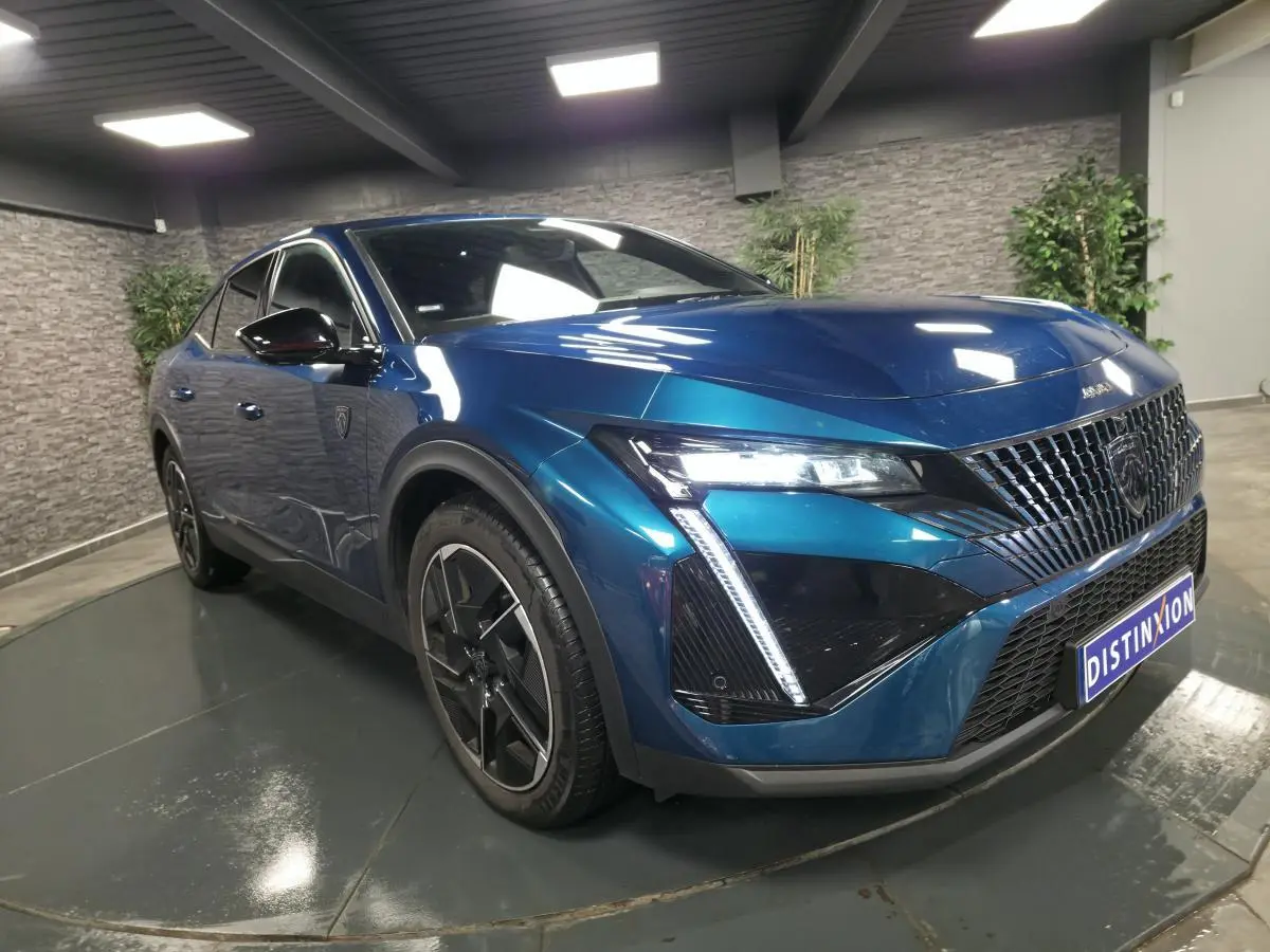 Vue 3/4 avant droite d'une Peugeot 408 hybride rechargeable bleu métallisé avec calandre distinctive et feux LED griffés.