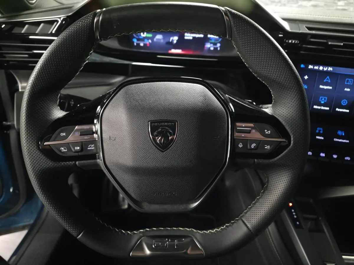 Vue rapprochée du volant cuir perforé noir avec logo Peugeot et commandes intégrées du Peugeot 408 GT 2024.