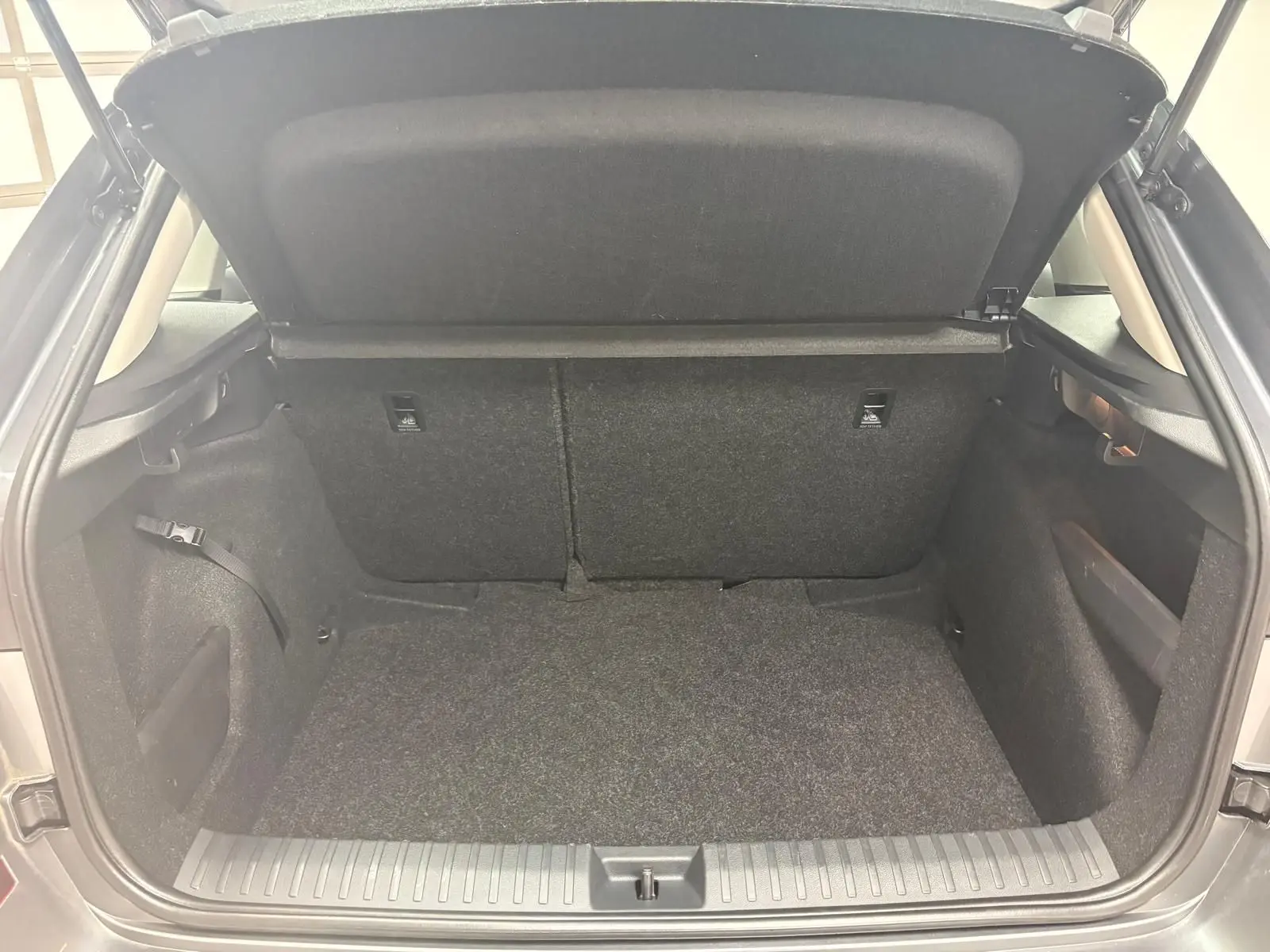 Coffre ouvert vu de l'arrière d'un Skoda Kamiq 2023 gris graphite, montrant l'espace de chargement vide et les dossiers arrière.