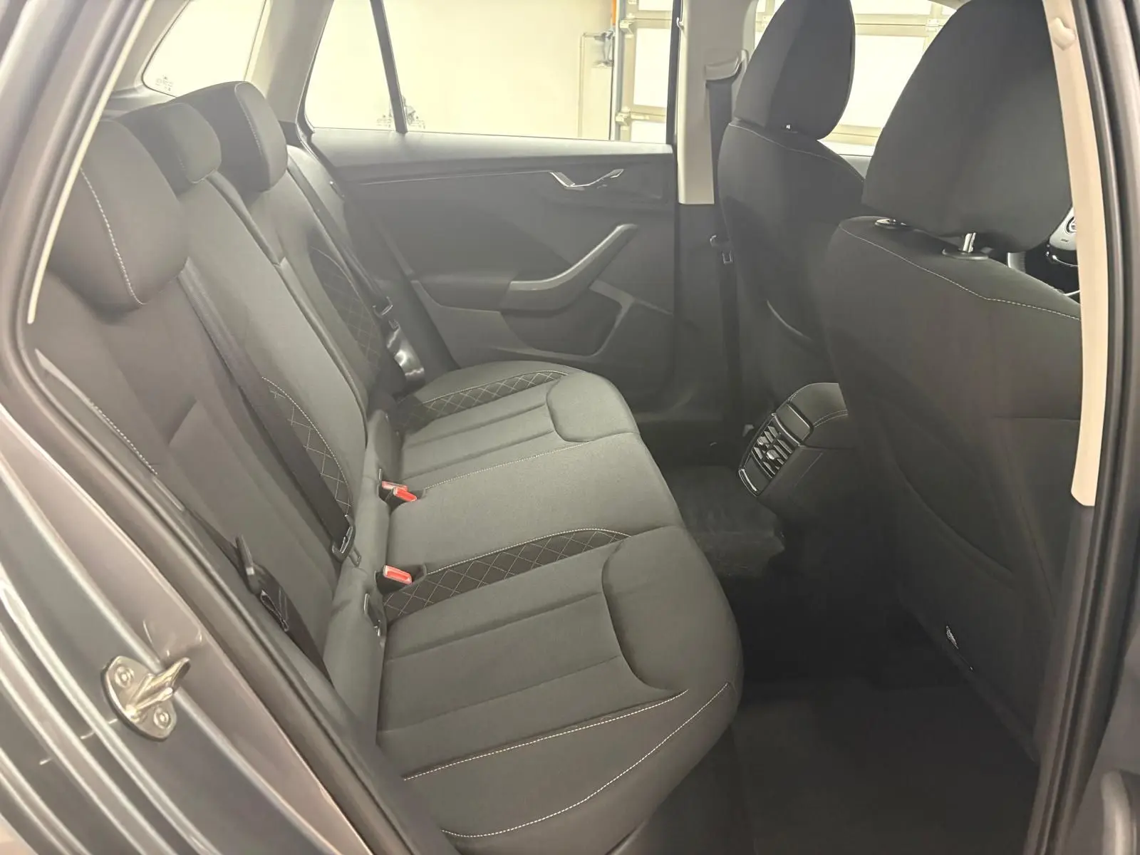 Vue intérieure côté arrière gauche du Skoda Kamiq 2023, sièges tissu noirs avec surpiqûres contrastées.