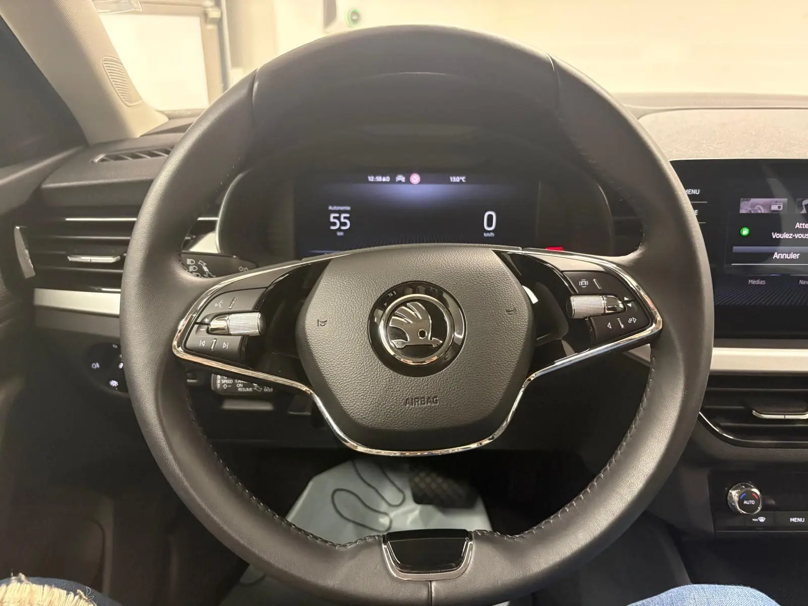 Vue intérieure centrée sur le volant noir de la Skoda Kamiq 2023 avec tableau de bord digital et commandes intégrées.