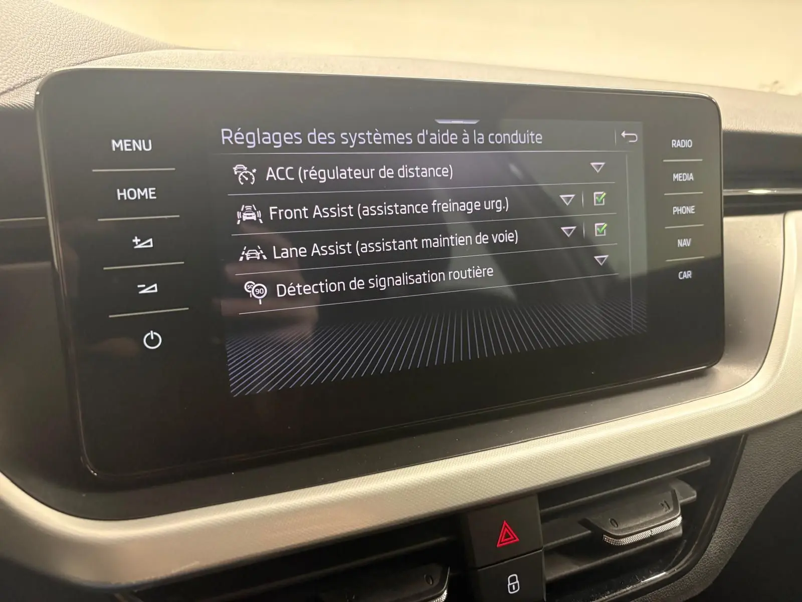 Écran central du Skoda Kamiq 2023 affichant les réglages des aides à la conduite dans l'habitacle.