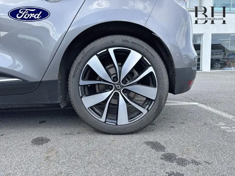 Gros plan sur la roue arrière droite du Renault Scénic gris Cassiopée avec jante alu bicolore noir et argent.