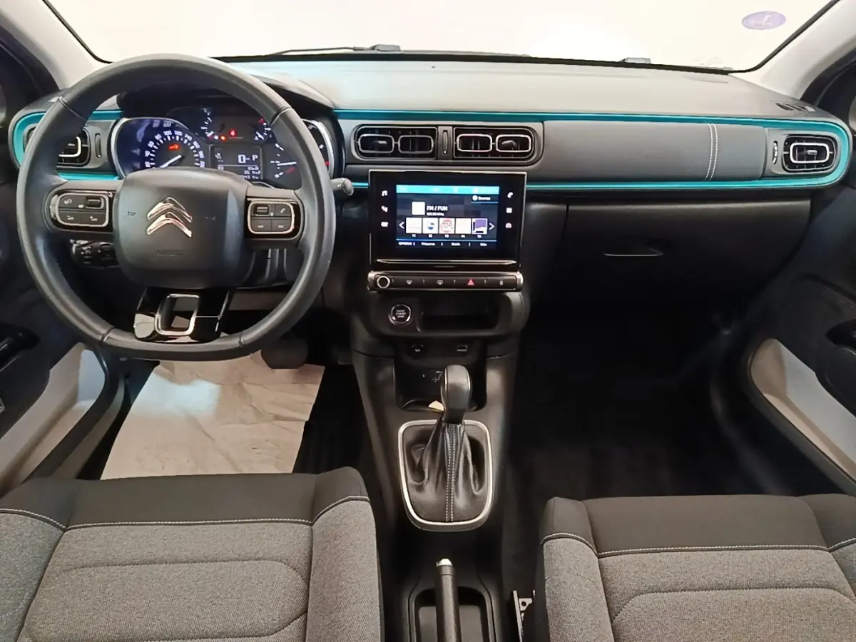 Vue intérieure avant de la Citroën C3 2022, tableau de bord noir avec bande décorative turquoise et écran tactile central.
