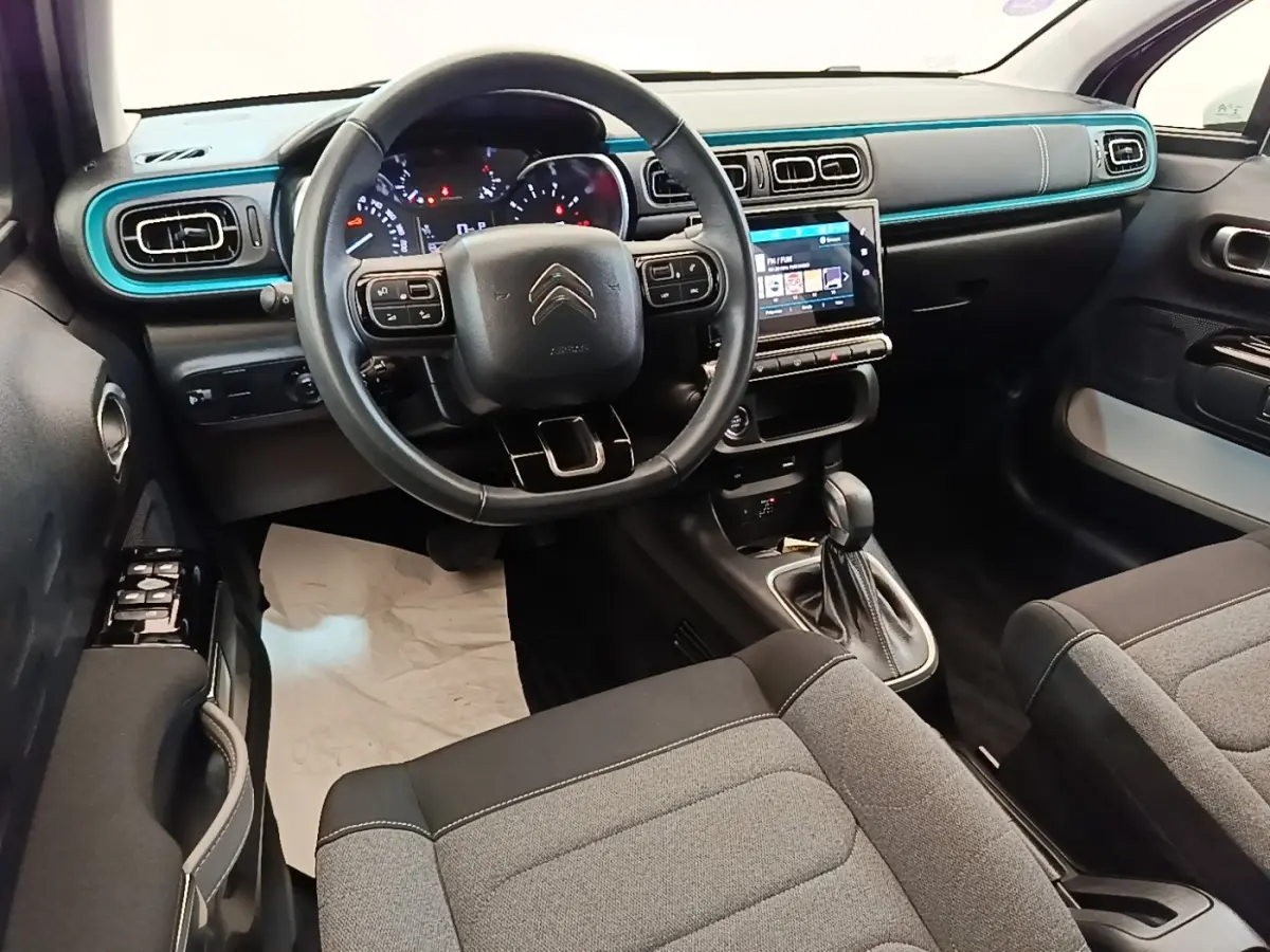 Vue intérieure avant droite du tableau de bord noir et bleu turquoise de la Citroën C3 2022 avec volant cuir et écran tactile.