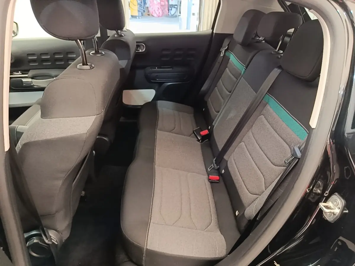 Vue intérieure côté droit sur la banquette arrière grise avec bandeau vert d'une Citroën C3 noire 2022.