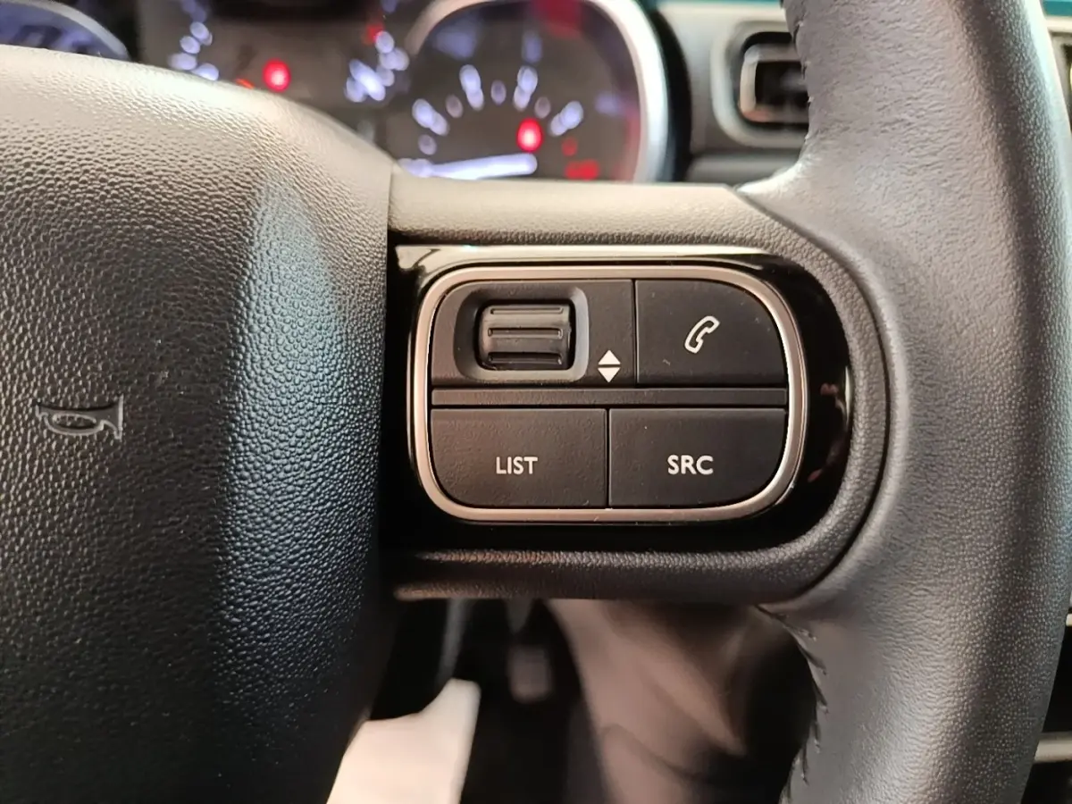 Gros plan sur les commandes du volant cuir noir de la Citroën C3 2022, boutons de gestion audio et appel.