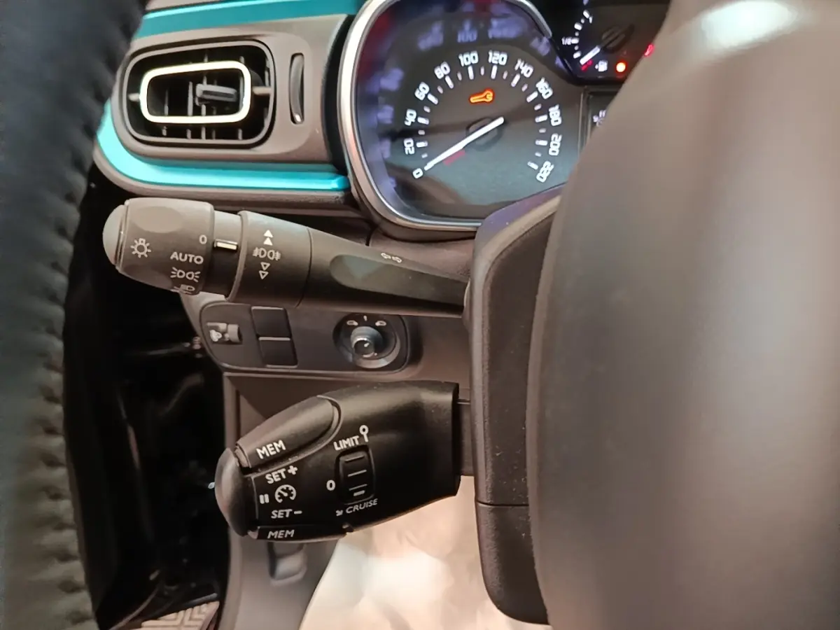 Vue rapprochée du tableau de bord côté gauche d’une Citroën C3 noire, avec commandes de régulateur et compteur lumineux.