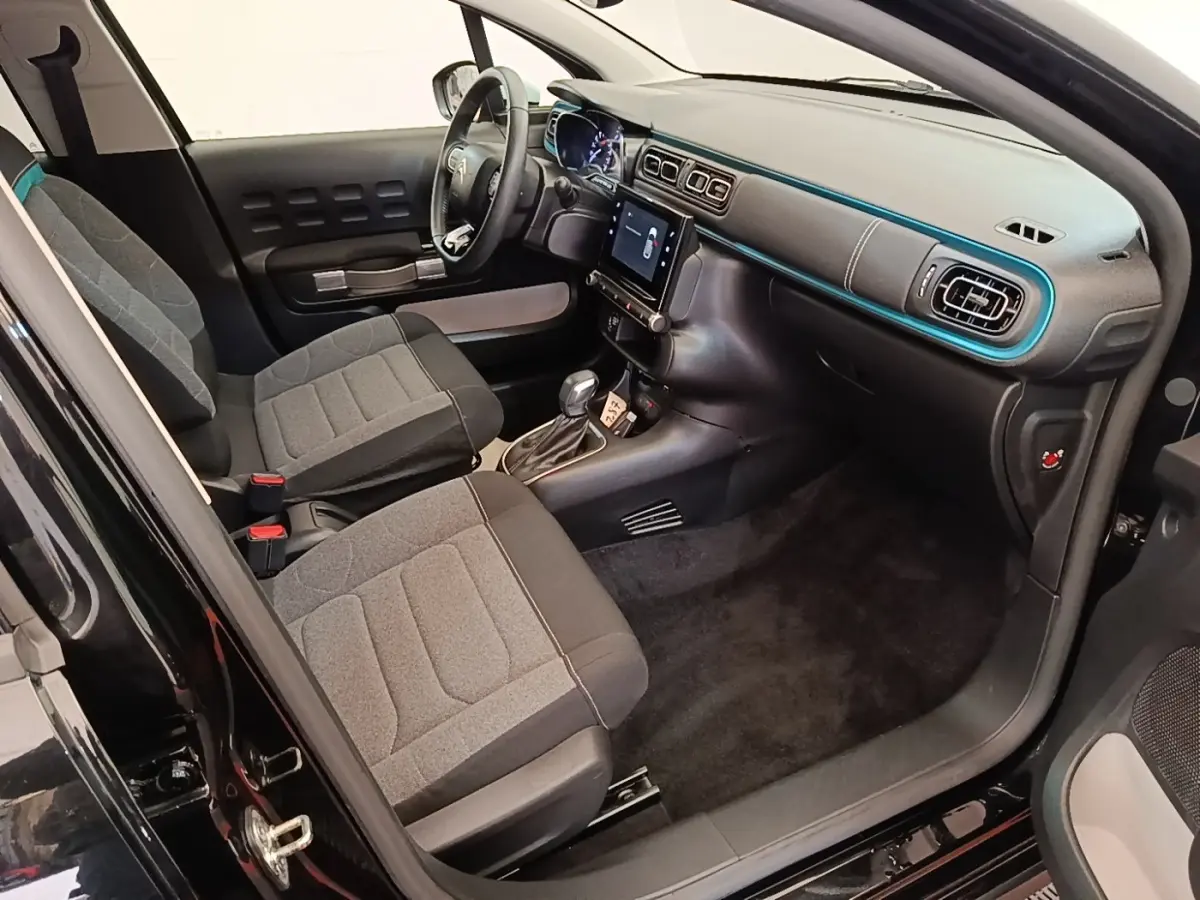 Intérieur avant droit d’une Citroën C3 noire 2022, montrant sièges gris, tableau de bord avec écran tactile et volant multifonctions.