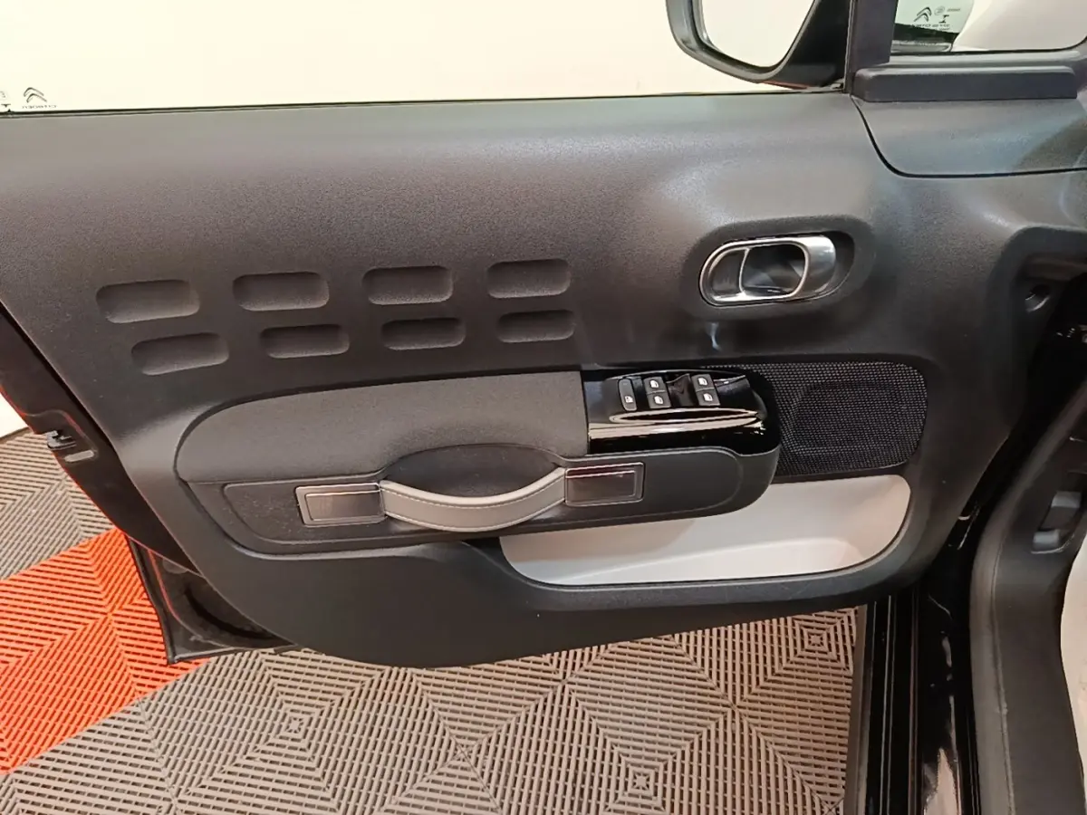 Vue rapprochée de la porte avant gauche noire de la Citroën C3 2022, avec commandes de vitres et poignée intégrée.