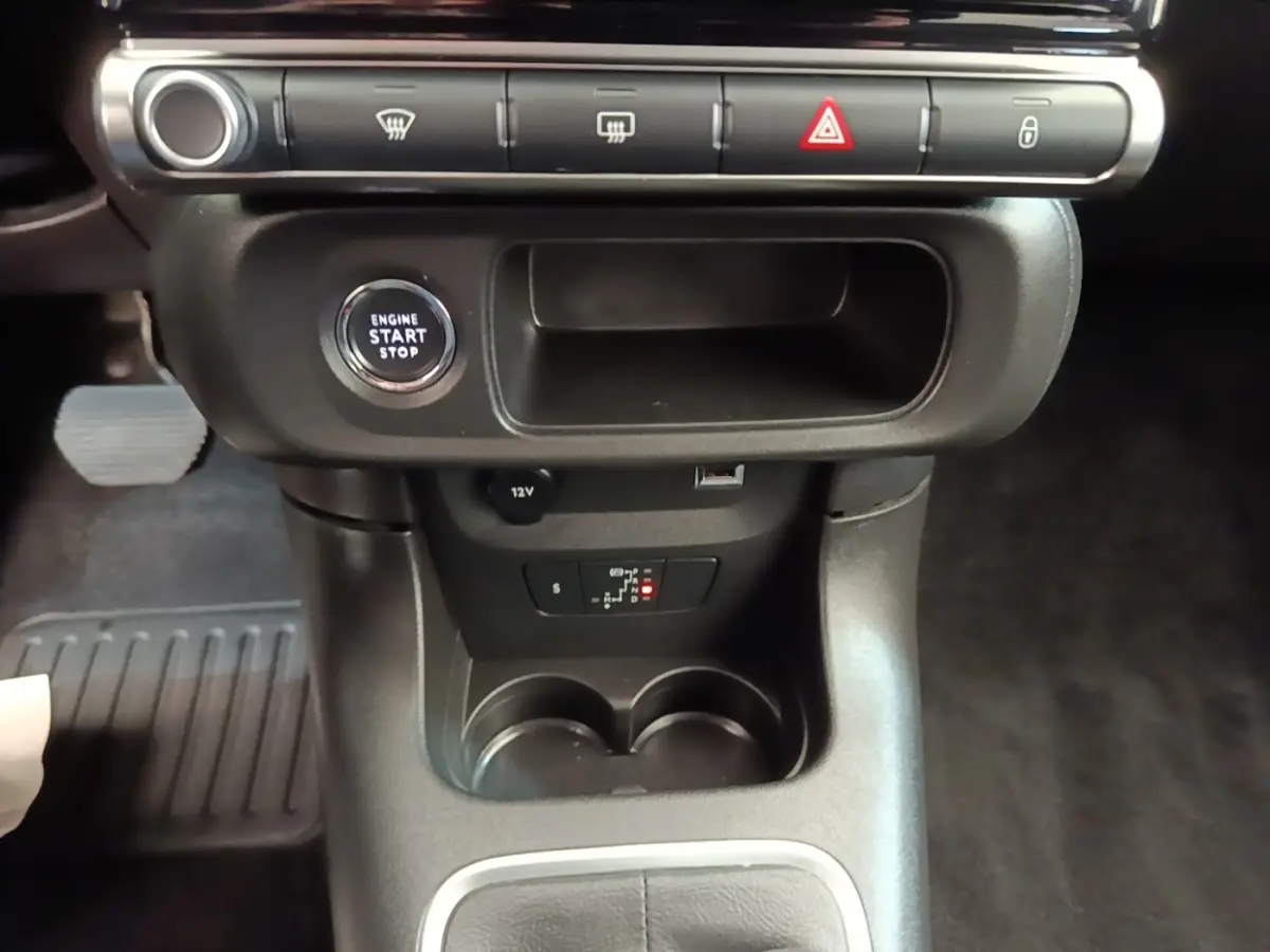 Gros plan intérieur sur la console centrale noire de la Citroën C3, avec bouton start/stop et prises 12V et USB visibles.
