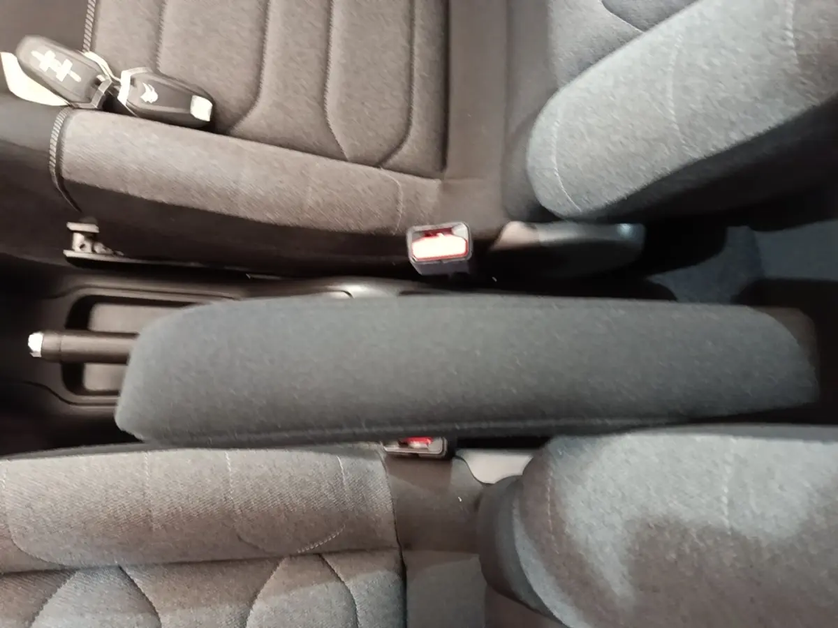 Vue plongeante sur l'accoudoir central et sièges avant en tissu gris foncé de la Citroën C3 noire.
