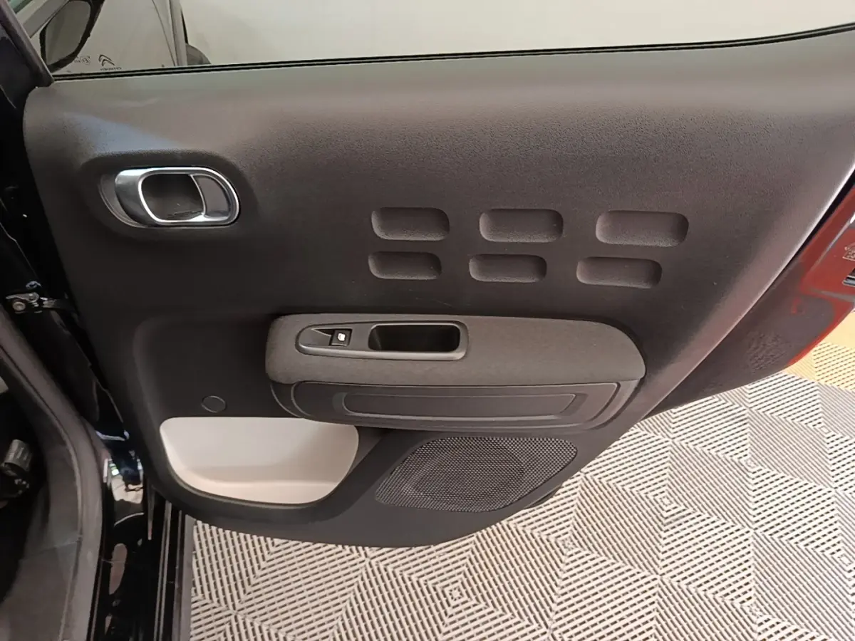 Vue intérieure de la porte arrière gauche noire d'une Citroën C3 2022 avec panneau de commande et haut-parleur intégré.