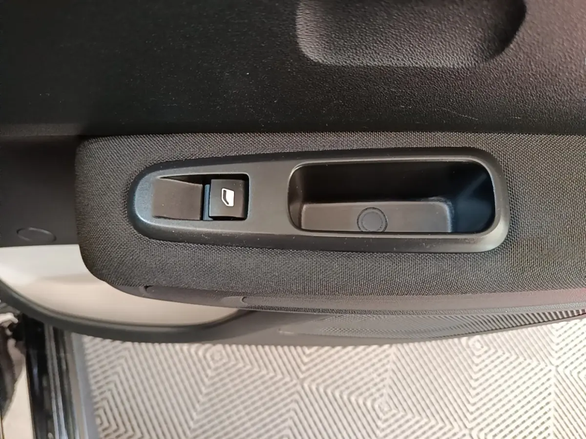 Gros plan sur la poignée intérieure et le bouton de lève-vitre côté gauche d’une Citroën C3 noire.