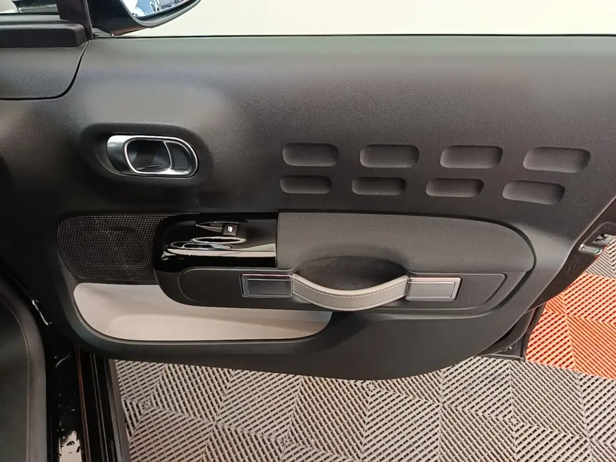 Vue rapprochée de la porte côté gauche de la Citroën C3 noire, avec poignée et commandes de vitre en noir brillant.