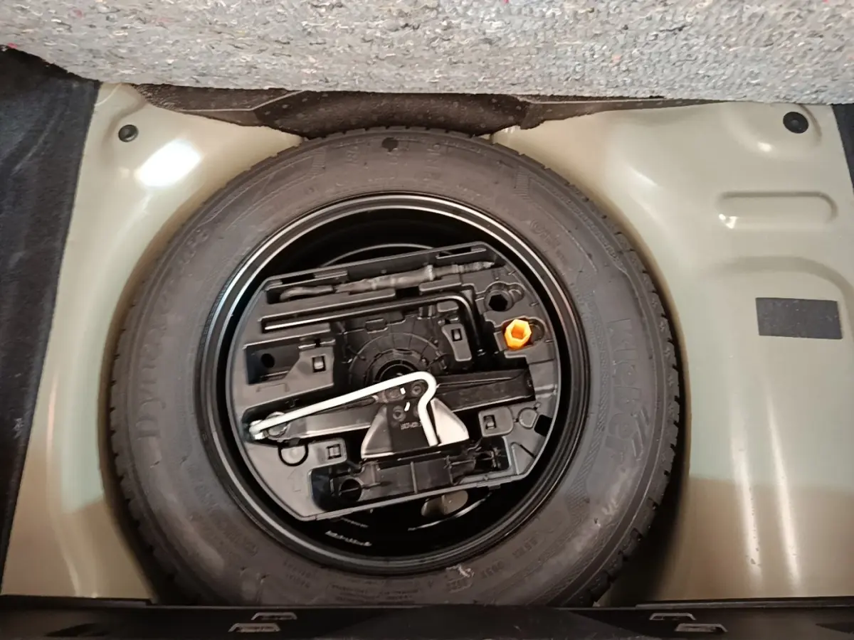 Gros plan sur la roue de secours et son rangement sous le plancher du coffre d'une Citroën C3 noire 2022.