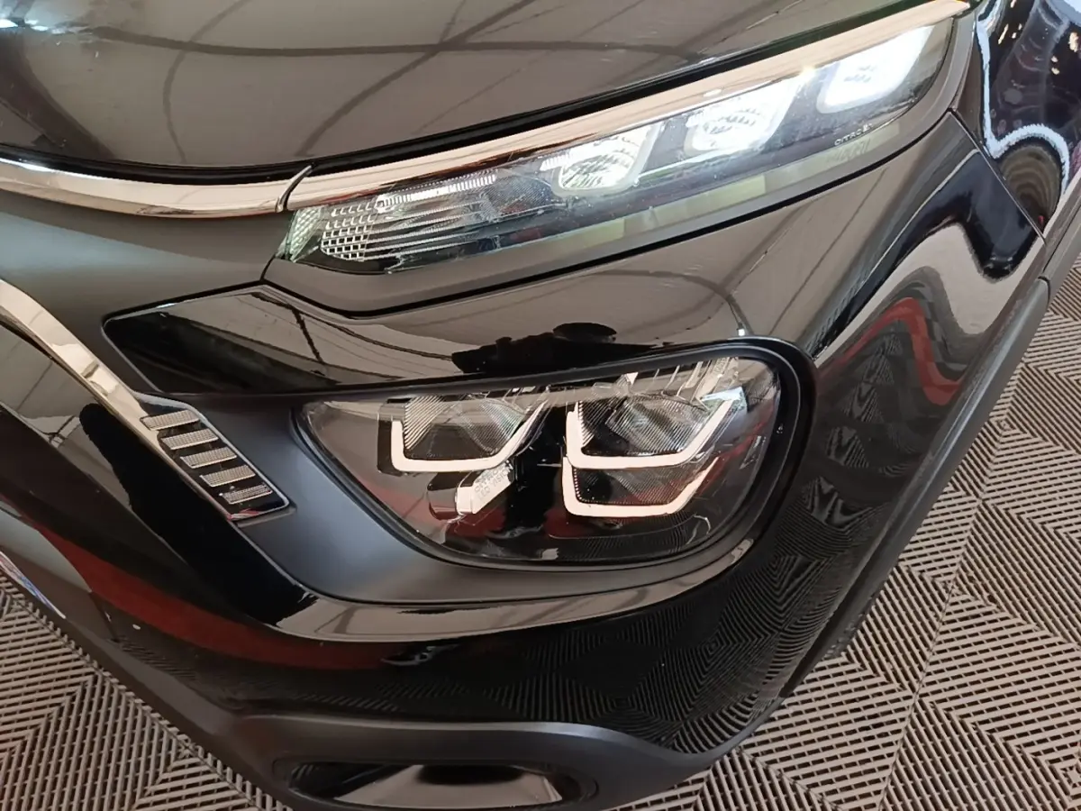 Gros plan sur le phare avant droit noir brillant de la Citroën C3 PureTech 110 Shine Pack 2022 avec éclairage LED distinctif.