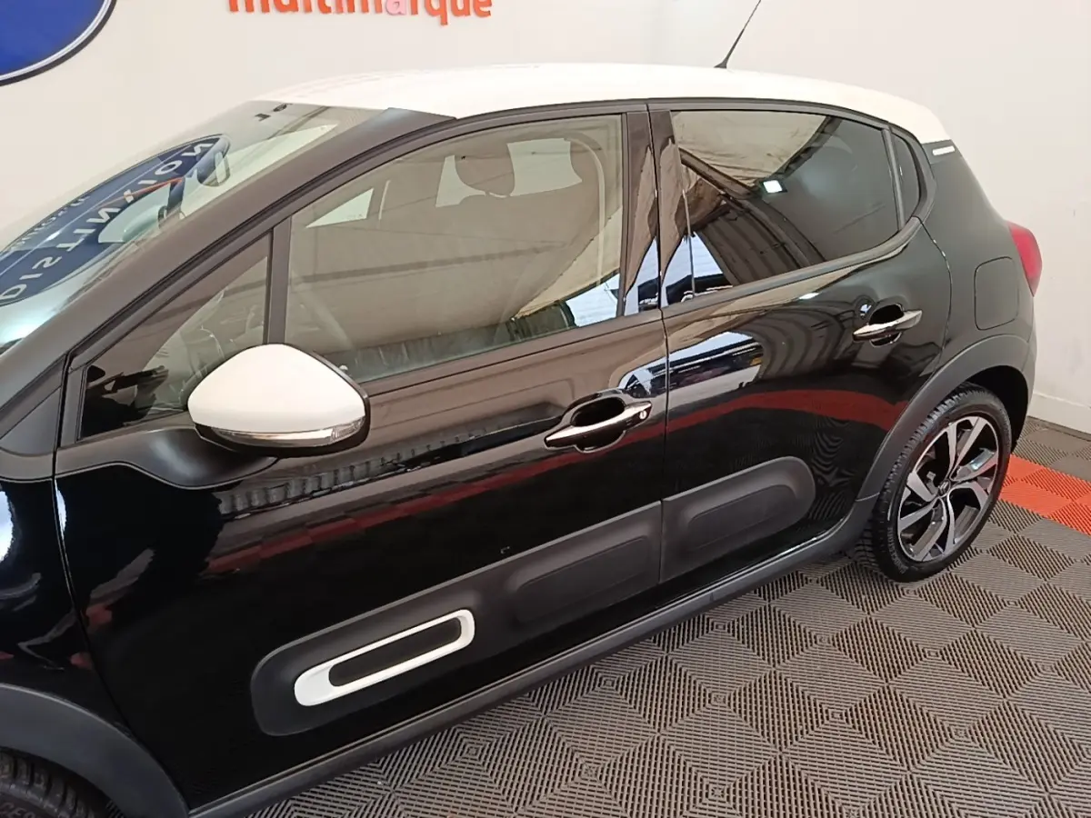 Vue latérale droite d'une Citroën C3 noire avec toit blanc et rétroviseur blanc, soulignant les protections latérales.