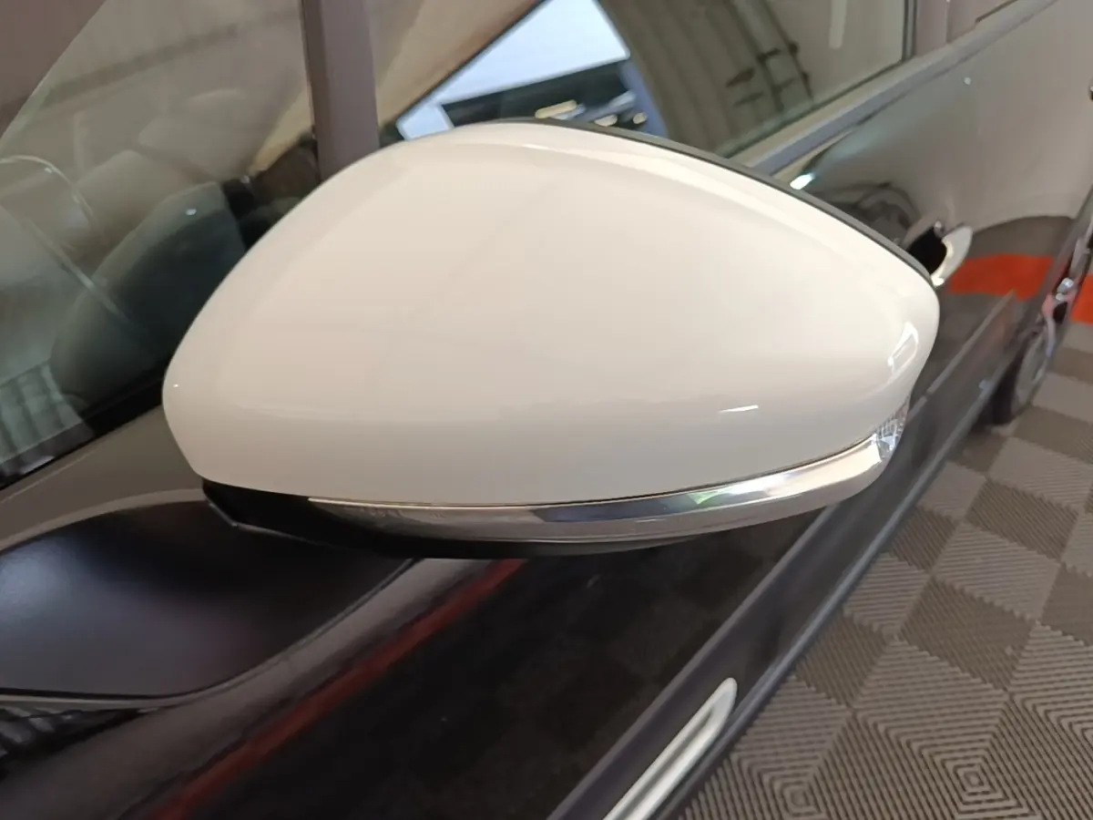Gros plan sur le rétroviseur blanc côté gauche d'une Citroën C3 noire, avec clignotant intégré chromé.