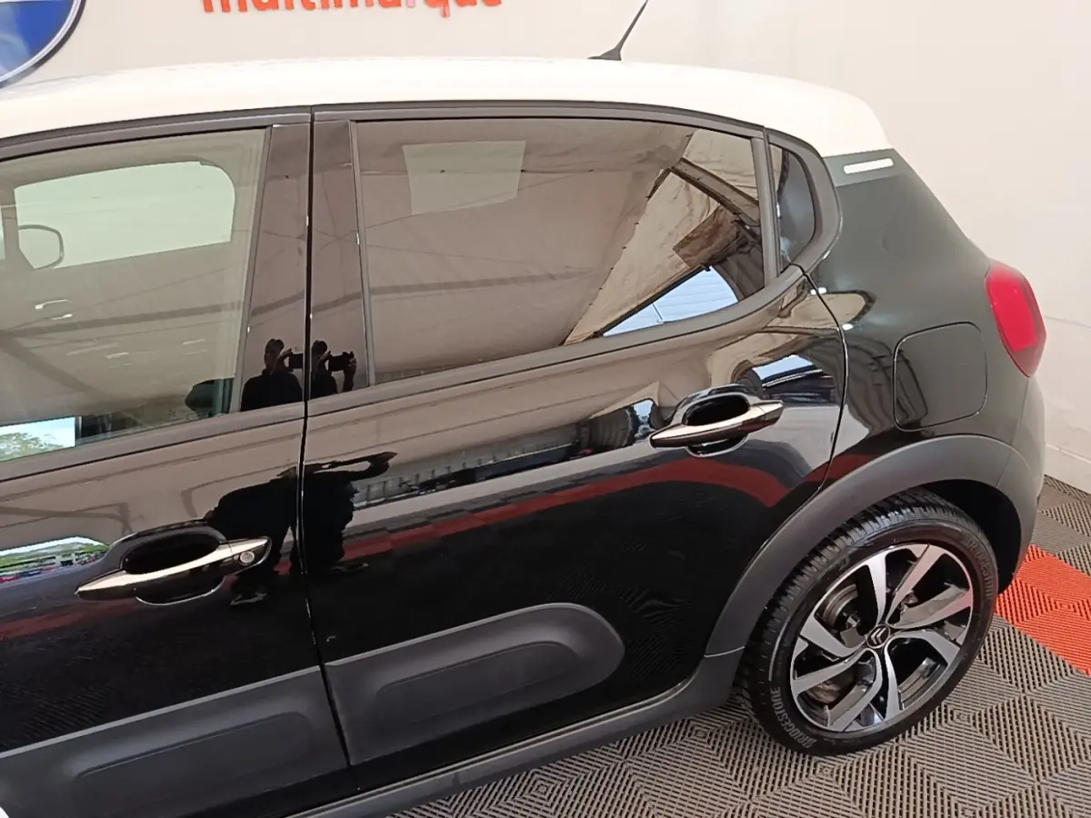 Vue latérale droite d'une Citroën C3 noire avec toit blanc et jantes alliage distinctives.