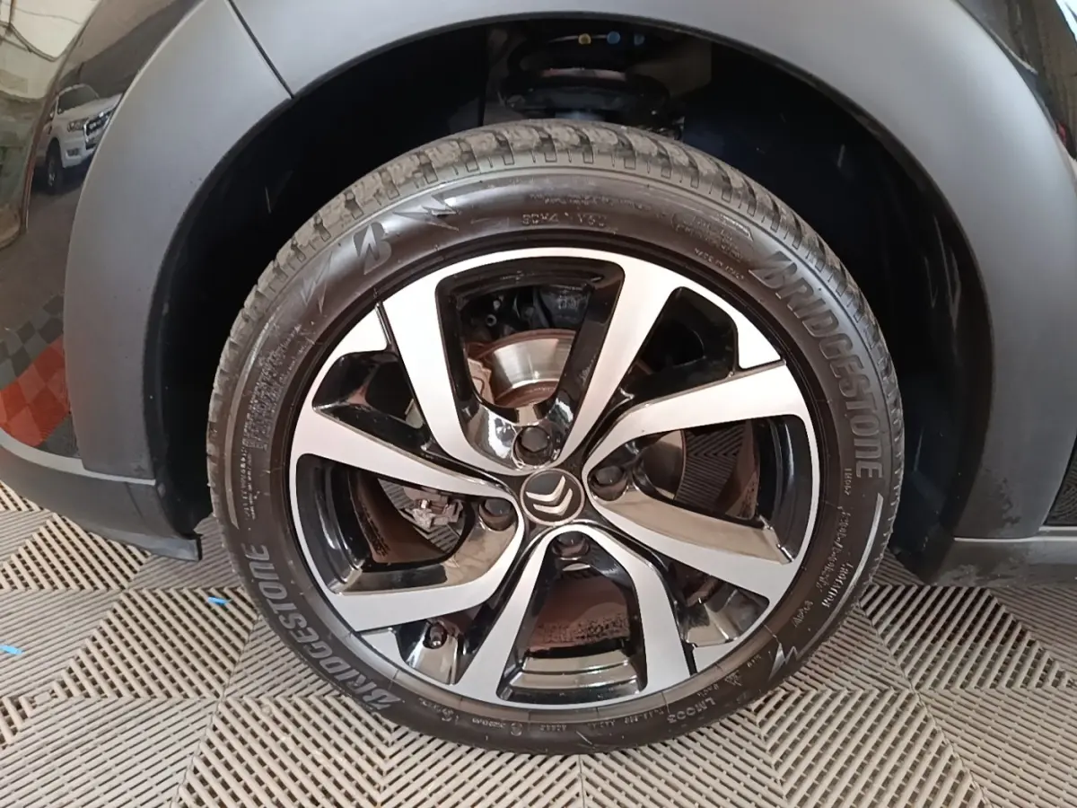 Gros plan sur la roue avant gauche noire d'une Citroën C3 2022 avec jante alliage bicolore et logo Citroën central.