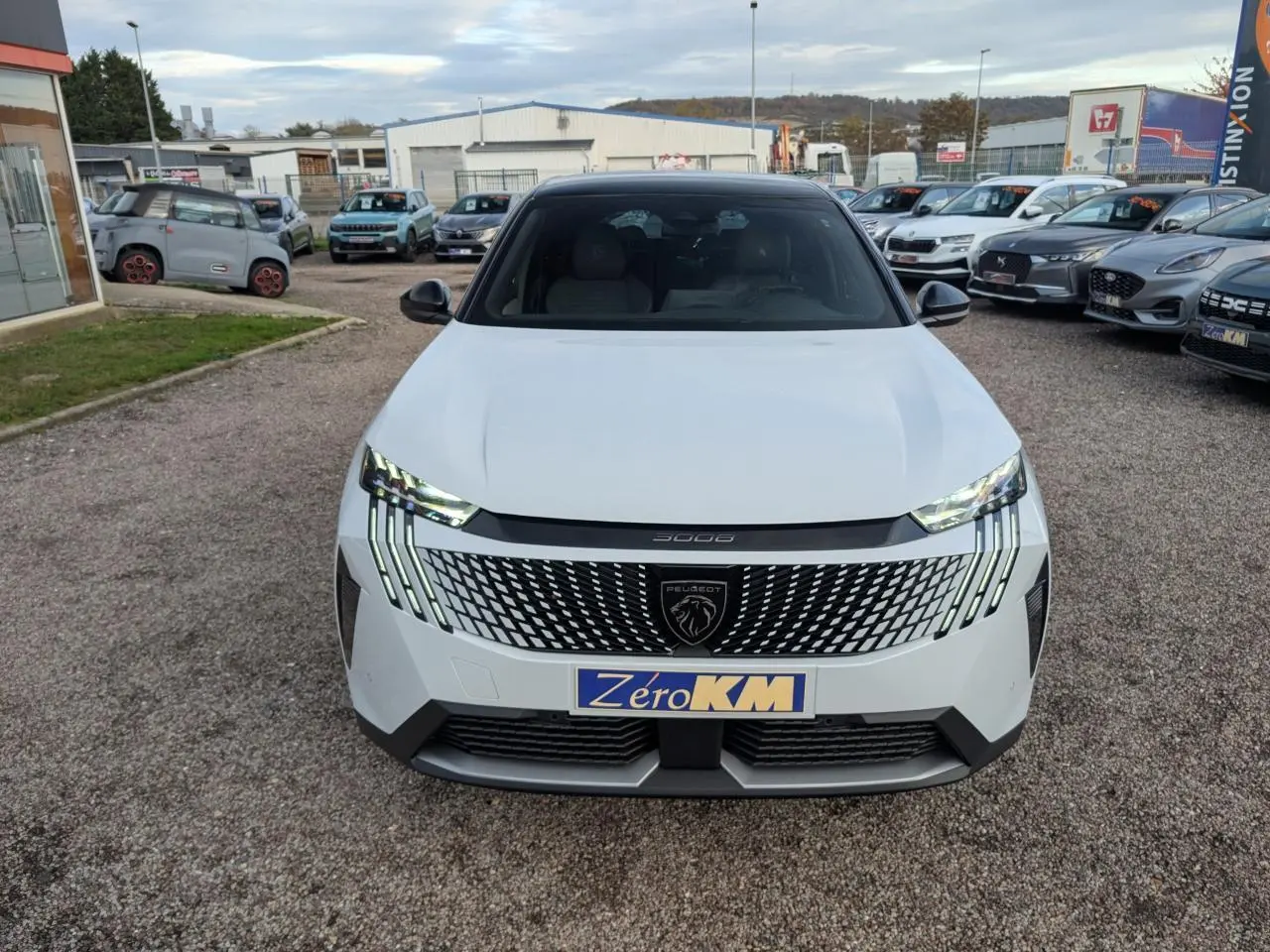 Vue avant d'un Peugeot 3008 blanc 2025 avec calandre noire à motif géométrique et feux LED griffés distinctifs.