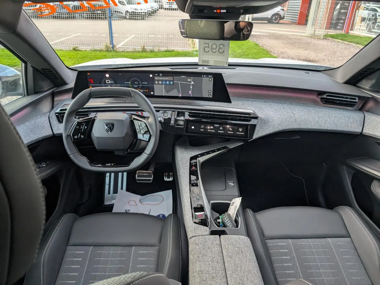 Vue intérieure avant du Peugeot 3008 blanc 2025 GT, avec tableau de bord numérique et sellerie tissu gris et noir.