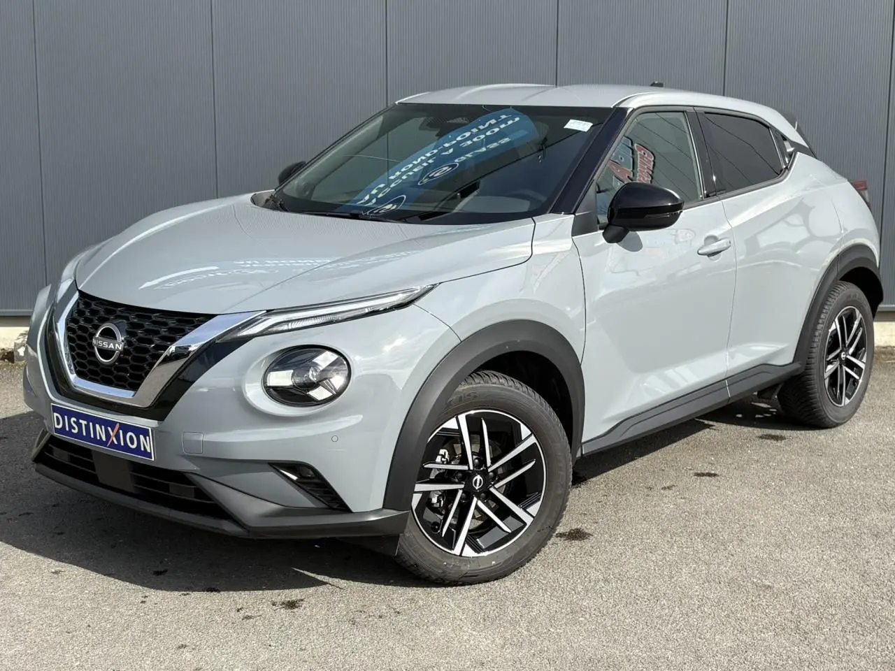 Nissan Juke gris Ceramic en 3/4 avant droit, avec jantes alliage noires et toit blanc contrasté.