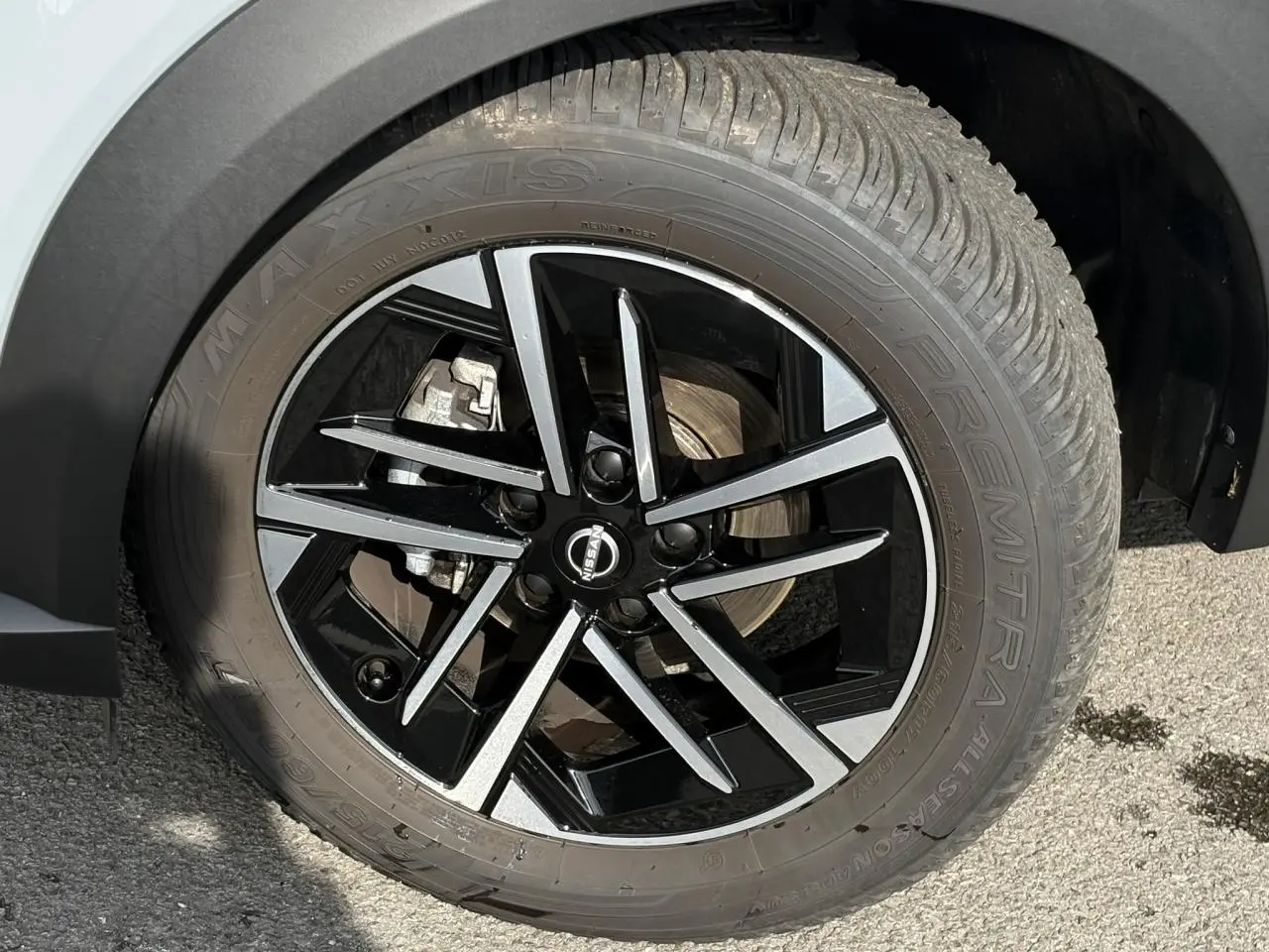 Gros plan sur la roue avant droite du Nissan Juke 2025 gris Ceramic avec jante alliage noire et argentée.