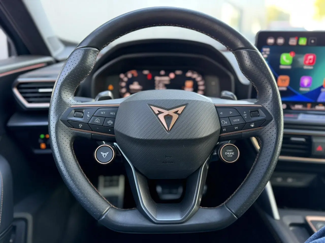 Gros plan sur le volant cuir noir perforé du CUPRA Formentor 2025 avec logo cuivre et commandes intégrées.