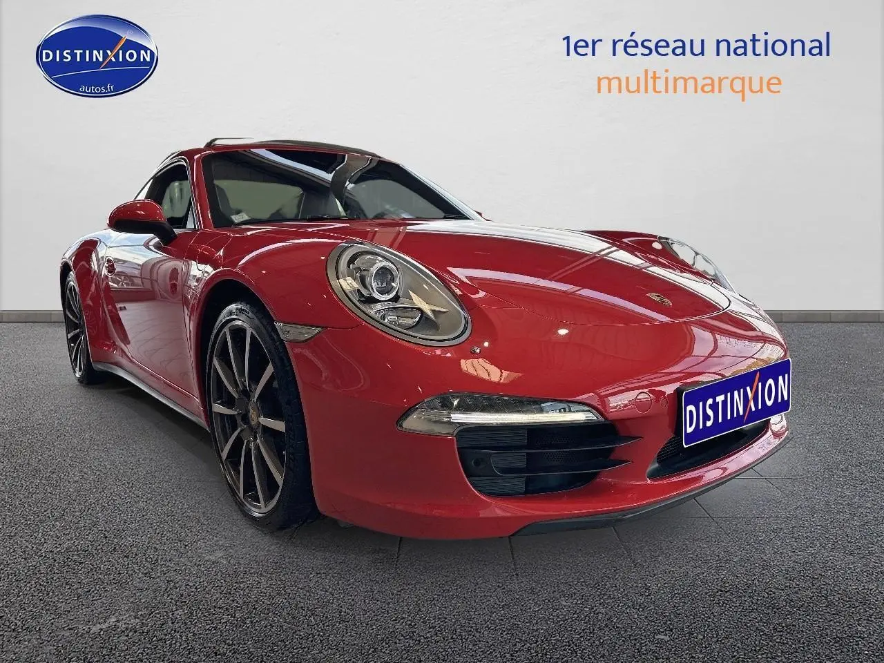 Porsche 911 (991) Carrera 4 rouge vue en 3/4 avant avec jantes alu et phares bi-xénon allumés.