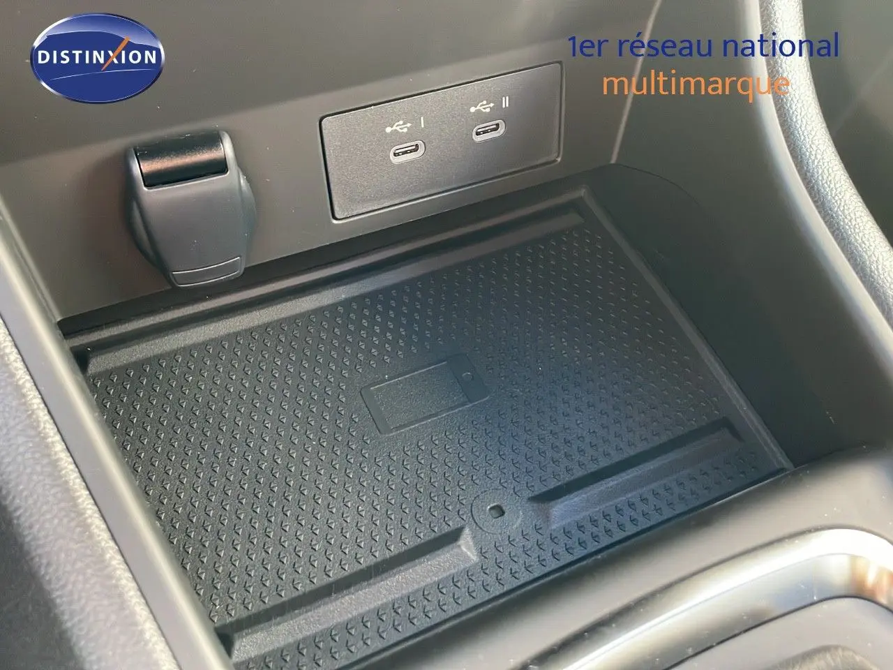 Gros plan sur la console centrale du Renault Captur 2025, montrant un espace de recharge avec ports USB et tapis antidérapant.