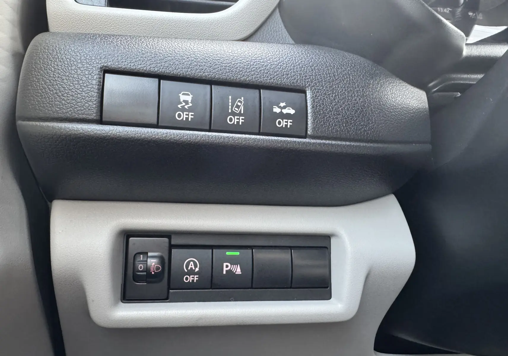 Panneau de commandes avec boutons d'assistance à la conduite dans l'habitacle d'une Suzuki Swift 1.2 Hybrid Privilege Auto bleu.